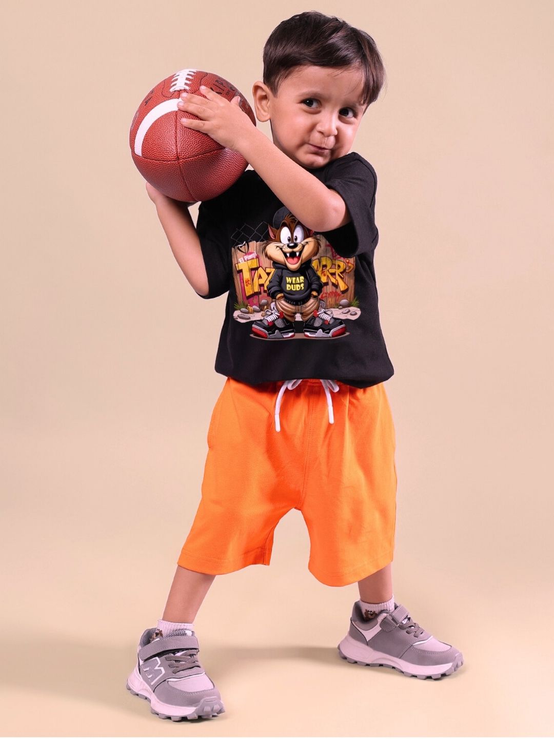 Child wearing Crazy Rapper black and orange co-ord set holding a football, showcasing urban-street style fashion for kids.