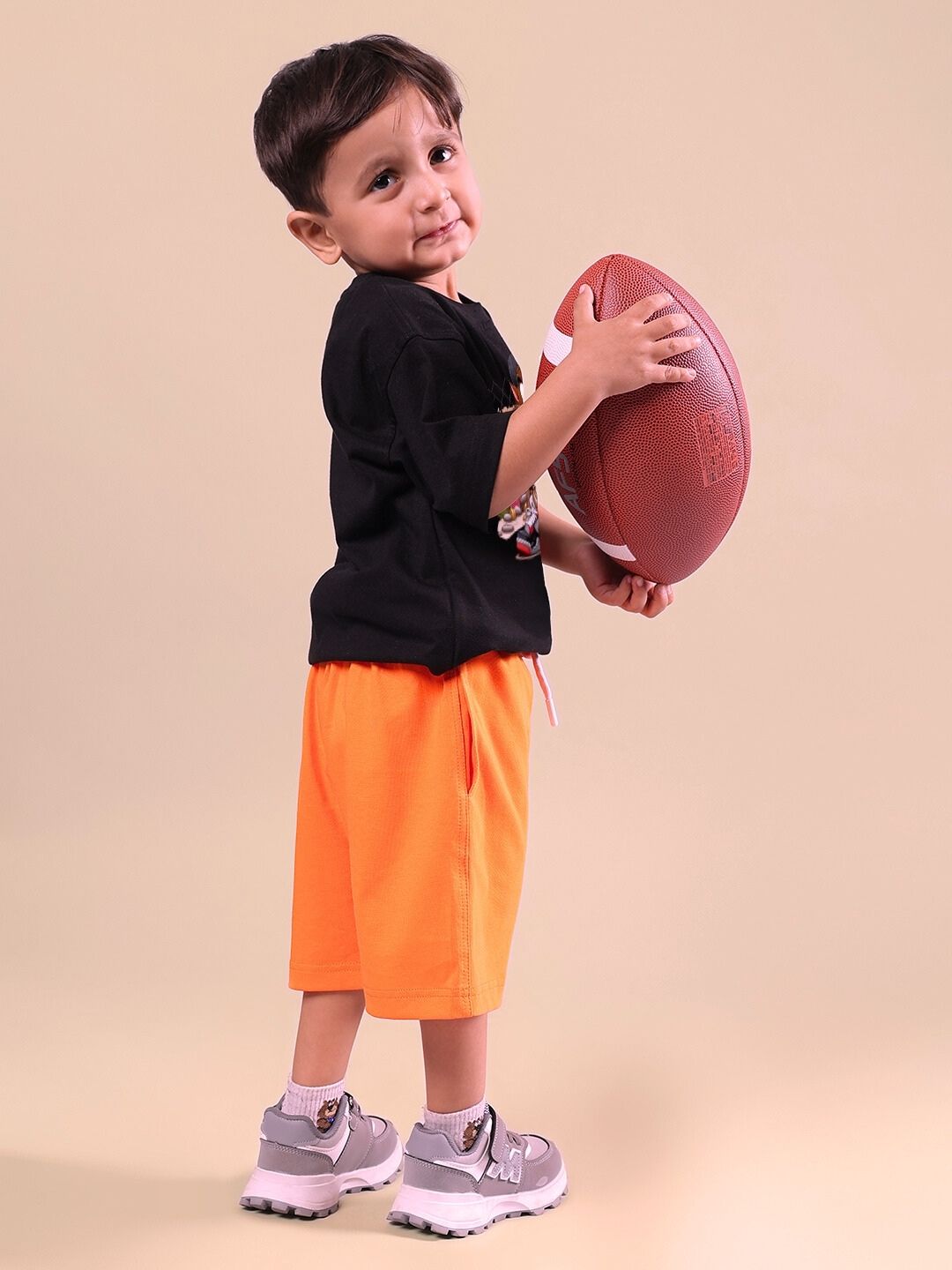 Child wearing Crazy Rapper co-ord set in black and orange, holding a football, showcasing urban street style fashion for kids.