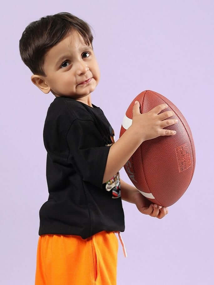 Young child wearing CRAZY RAPPER T-SHIRT FOR BOYS AND GIRLS BLACK holding a football, showcasing trendy casual wear for kids.