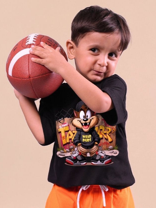 Child holding a football wearing a black Crazy Rapper T-shirt featuring a cartoon character, embodying urban street style for kids.