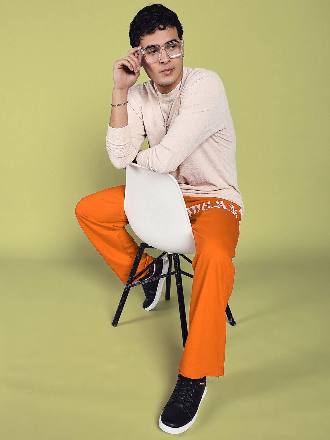Model wearing orange Crimson Relaxed Fit Jogger sitting stylishly with tailored comfort.