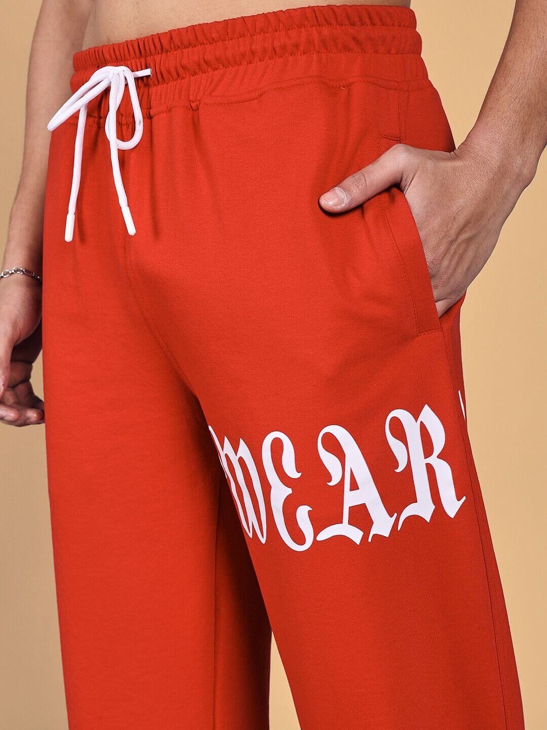 Close-up of crimson relaxed fit jogger pants with white drawstring, highlighting text detail on the side.