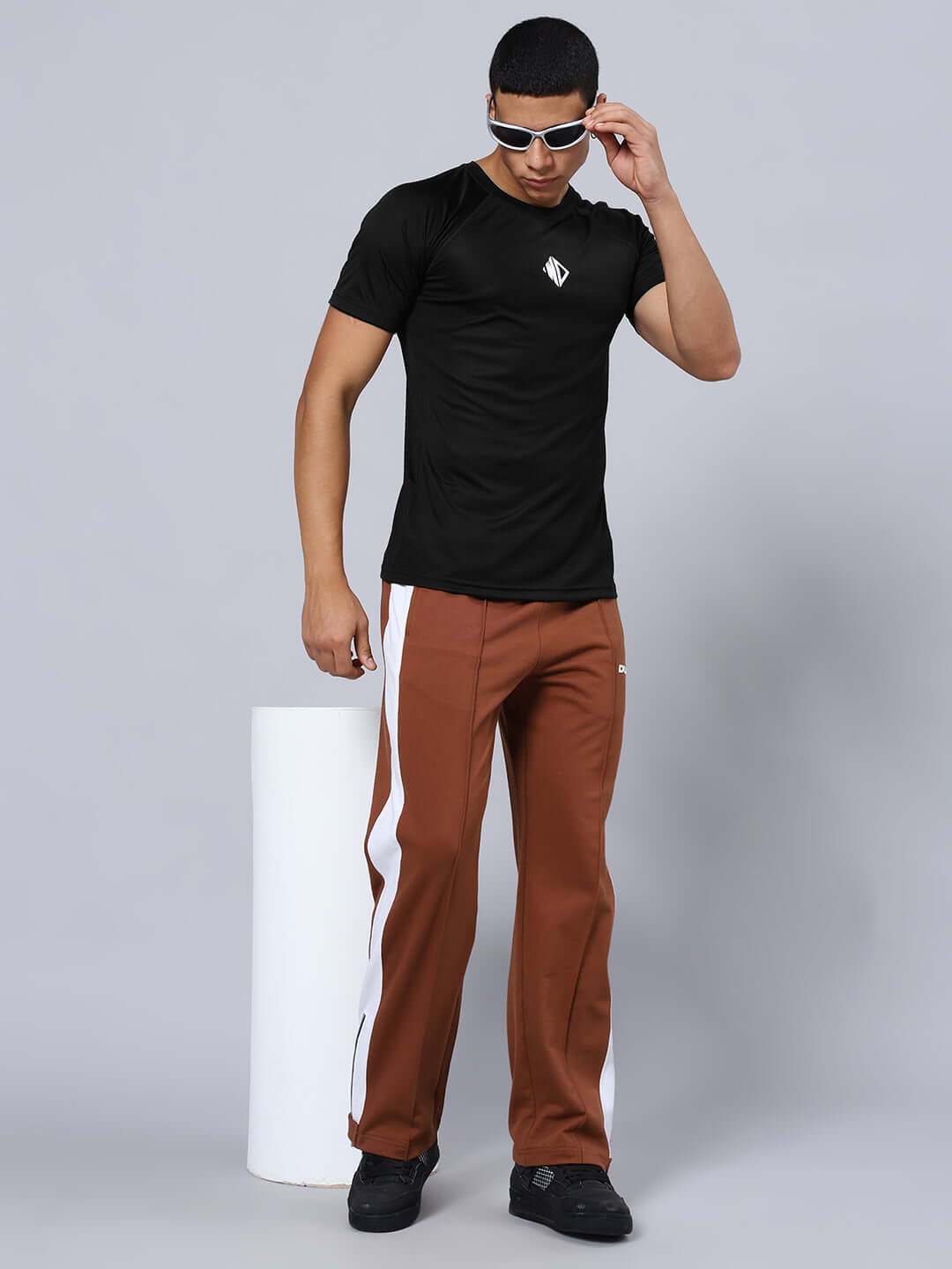 Man wearing CRISTINIO REGULAR FIT T-SHIRT BLACK with sunglasses, paired with brown pants, showcasing casual style.
