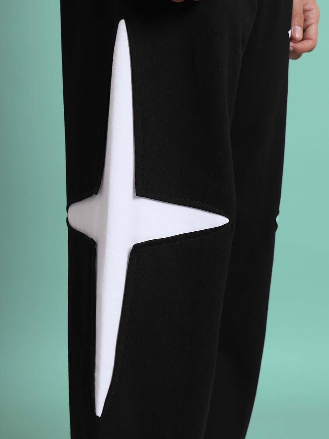 Close-up of black joggers featuring a distinctive white crossed star design, part of the made-to-order CROSSED STAR JOGGER collection.