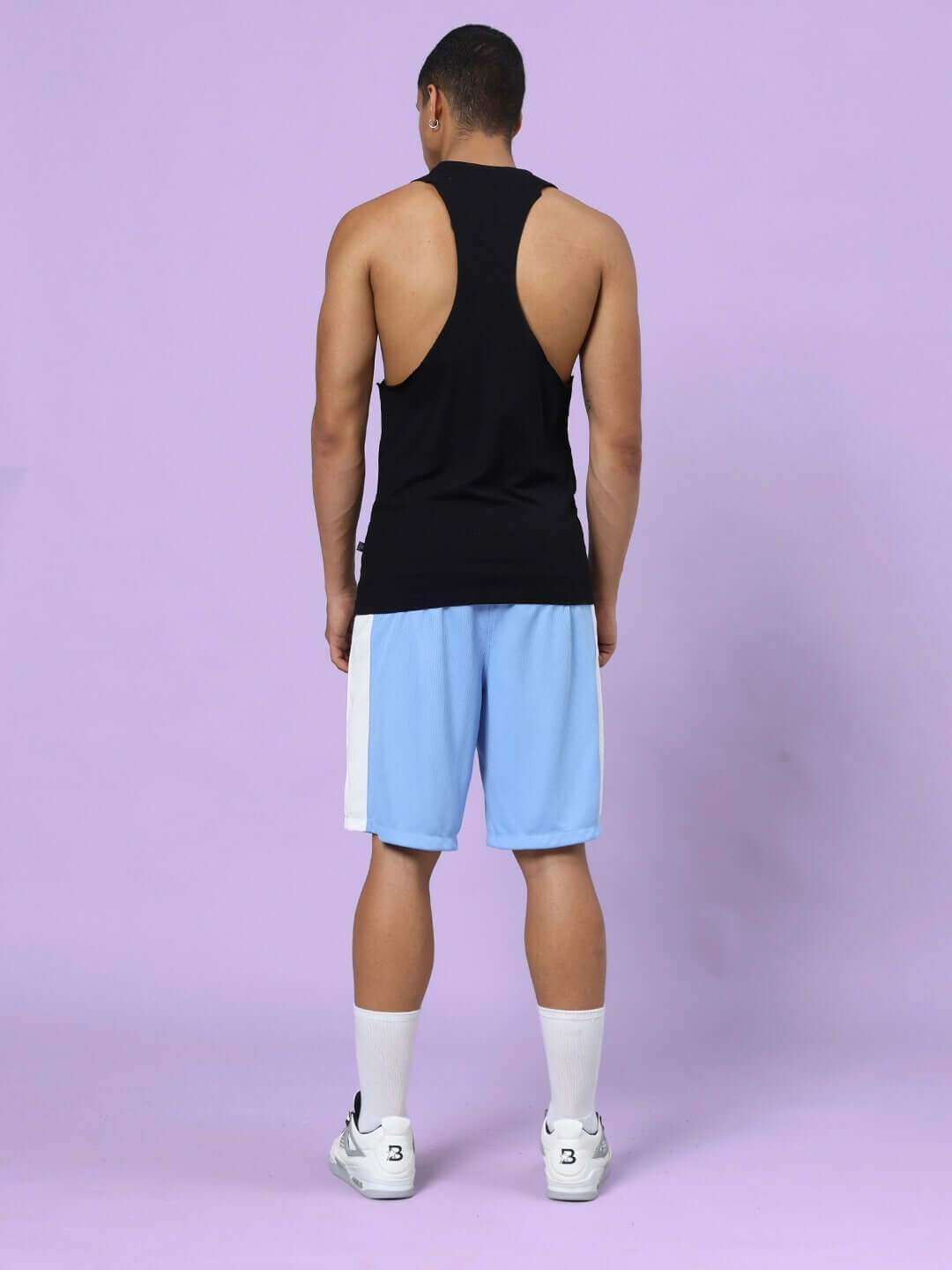 Back view of model wearing CRUNCH GYM CO-ORD SET BLACK-BLUE, featuring black top and blue shorts, showcasing athletic wear fashion.