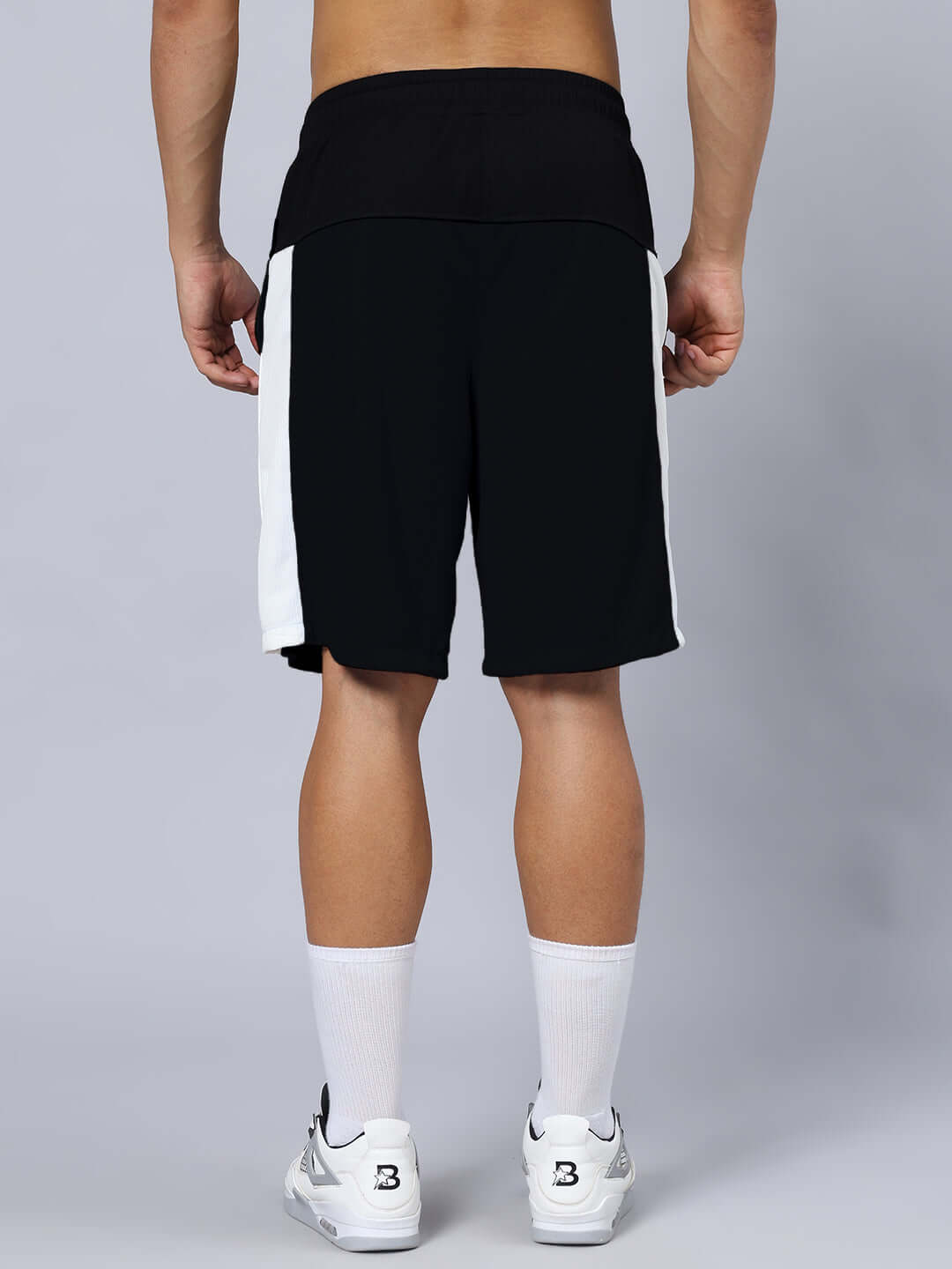 Back view of model wearing CRUNCH REGULAR FIT SHORTS BLACK with side white stripe, ideal for custom fit options and comfortable wear.
