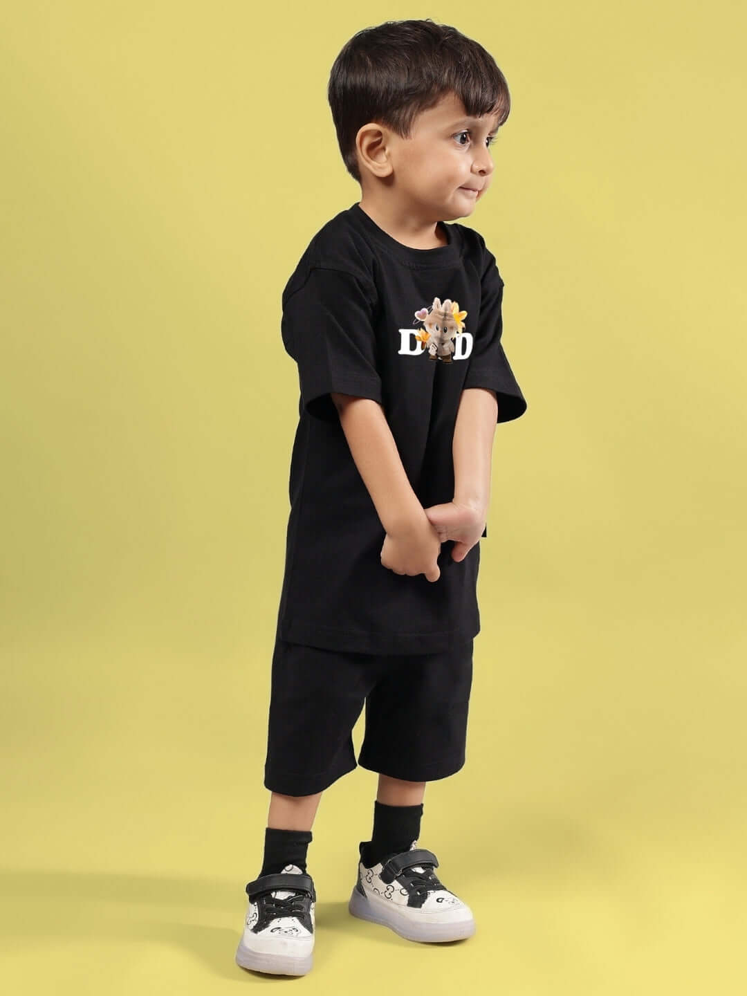 Young child modeling black Cute Monsters Co-ord from DUDS on yellow background.