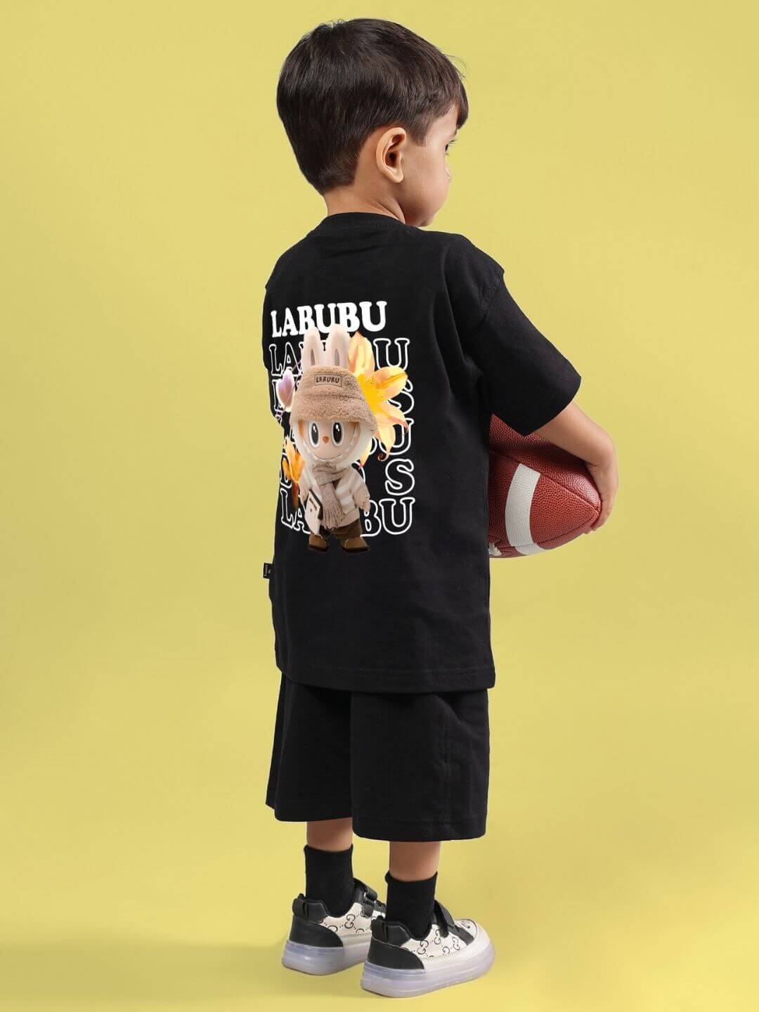 Child wearing CUTE MONSTERS CO-ORD FOR BOYS GIRLS BLACK with playful monster graphic, holding a football.