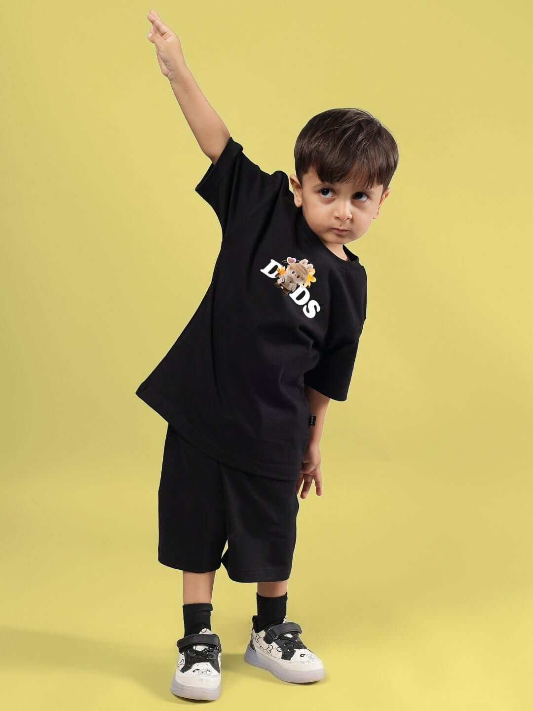 Child wearing CUTE MONSTERS CO-ORD FOR BOYS GIRLS BLACK with playful monster graphic on black outfit against yellow background.