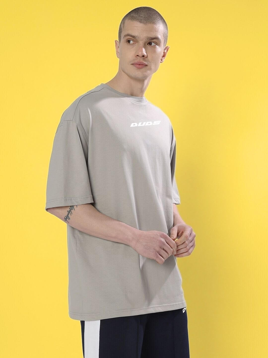 Man wearing CYBERPUNK OVER-SIZED T-SHIRT GREY with bold streetwear style against yellow background