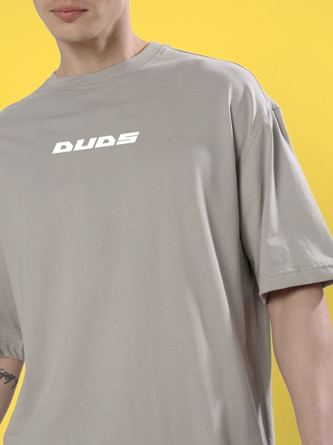 Person wearing CYBERPUNK OVER-SIZED T-SHIRT GREY with bold print, yellow background.