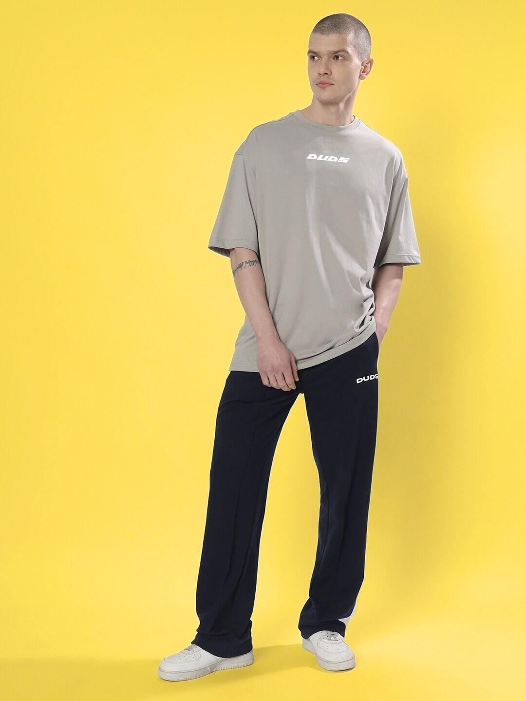 Model wearing CYBERPUNK OVER-SIZED T-SHIRT GREY with relaxed silhouette and urban style on yellow background.
