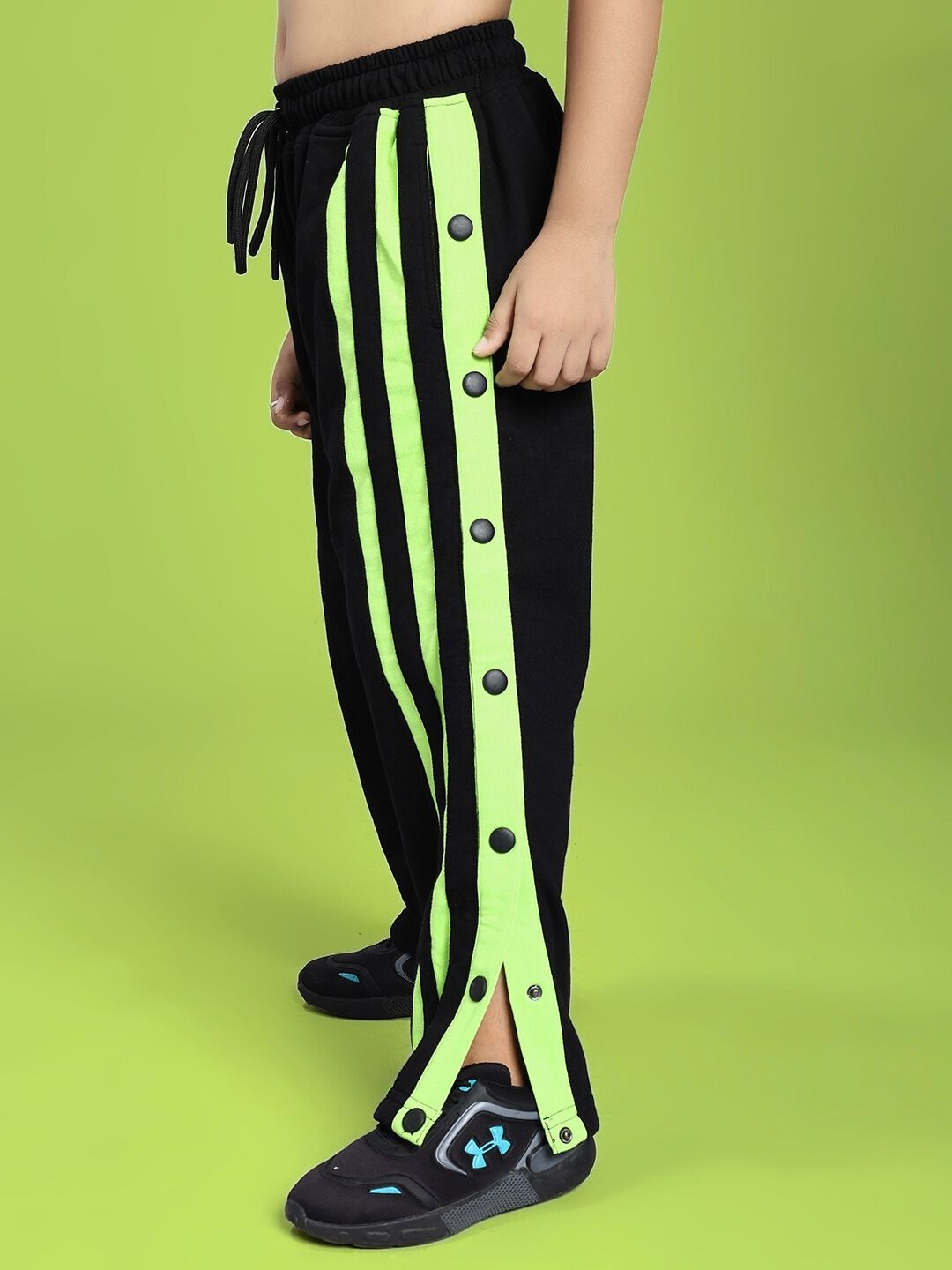 Child wearing DANCER JOGGER FOR BOYS AND GIRLS BLACK NEON-GREEN with button accents and stylish design.