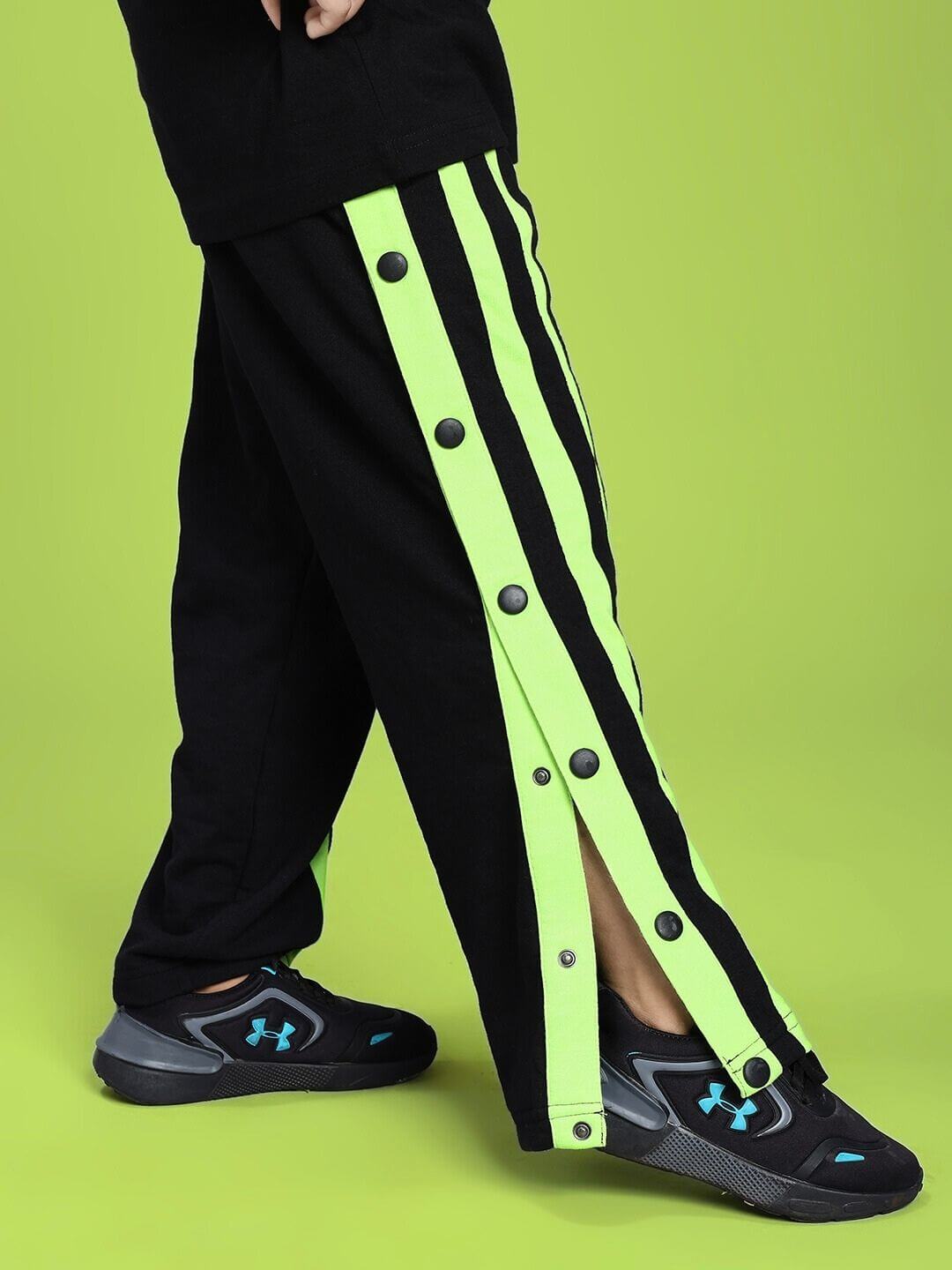 DANCER JOGGER FOR BOYS AND GIRLS BLACK NEON-GREEN with neon-green accents displayed on a child wearing sneakers against a green background.