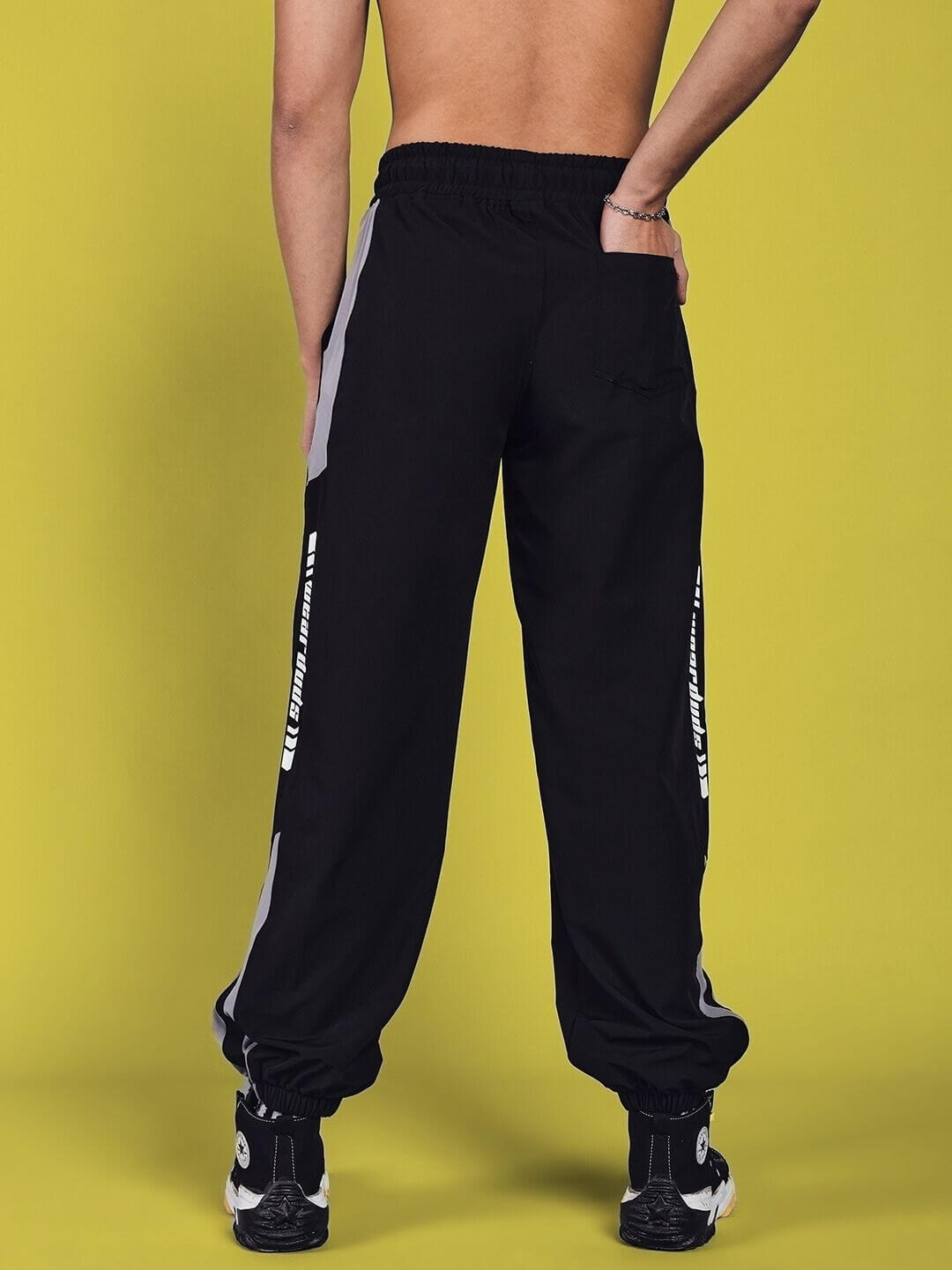 Back view of model wearing black Danny Relaxed Fit Cargo Pants with elastic waistband and printed detail.
