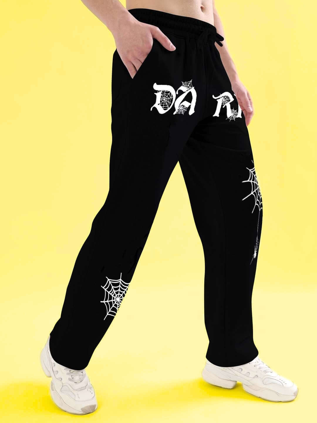 Model wearing black Dark Web relaxed jogger with spider web design, showcasing comfort and style on a bright yellow background.