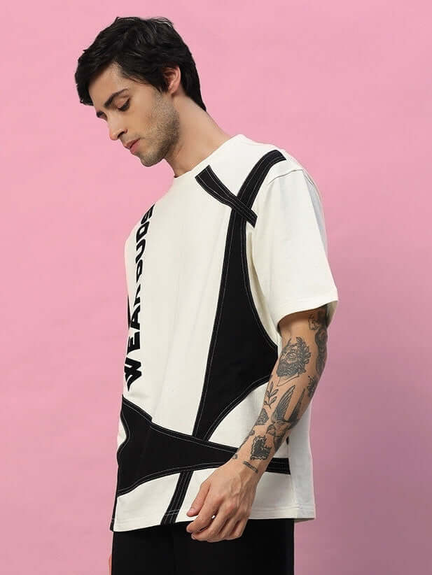 Man wearing DAVID DESIGNER OVERSIZED T-SHIRT OFF WHITE BLACK with modern print, pink background, stylish unisex fashion.