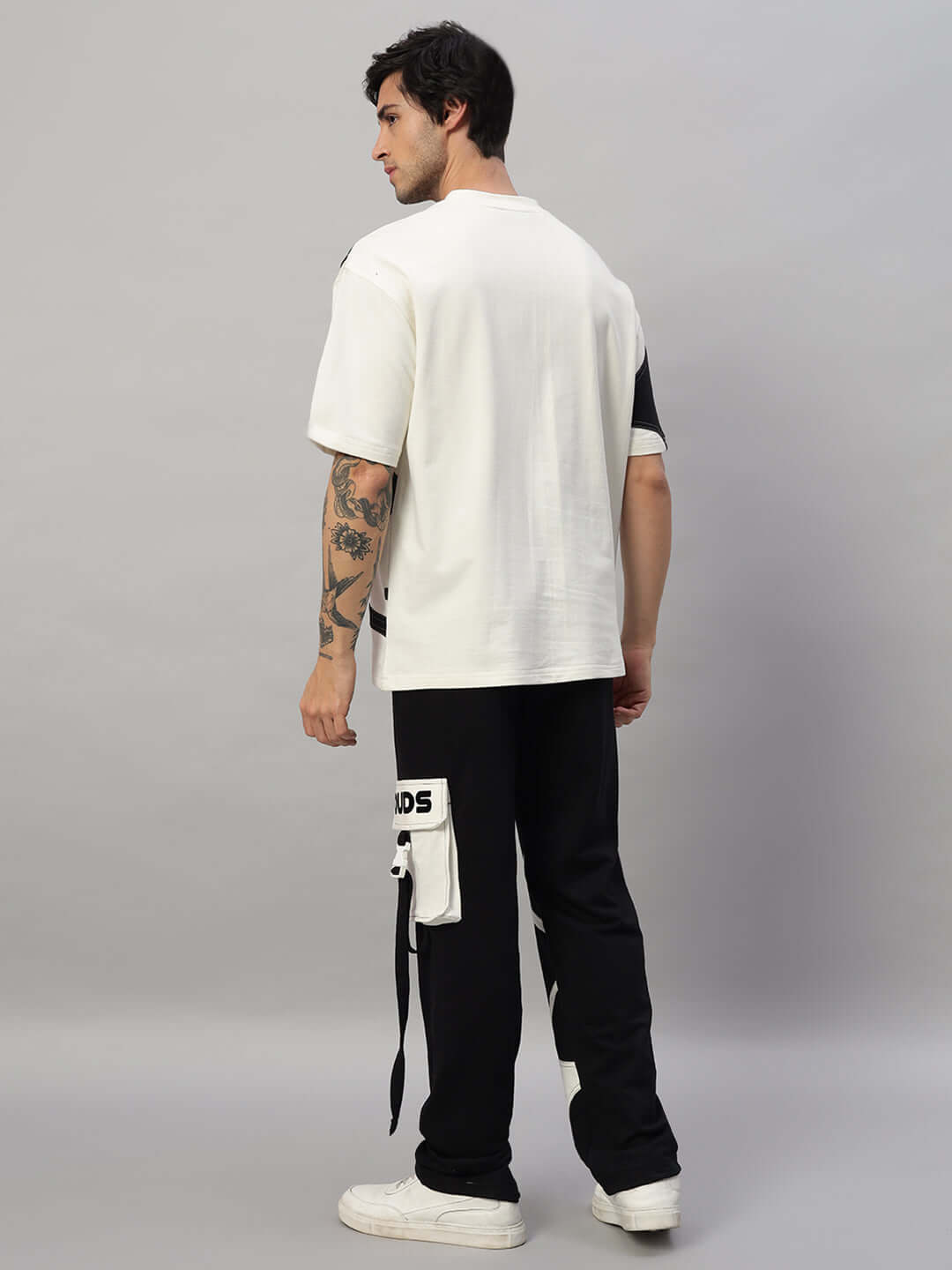 Model wearing oversized co-ord set in off white and black, featuring unisex relaxed fit joggers with elasticated waistband and drawstring.