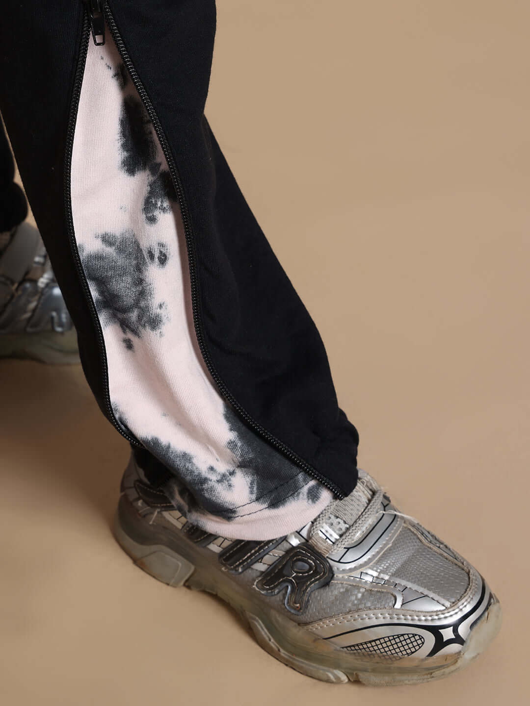 Close-up of black Deadpool joggers for kids with zip detail, highlighting custom fit option; shown with silver running shoes.