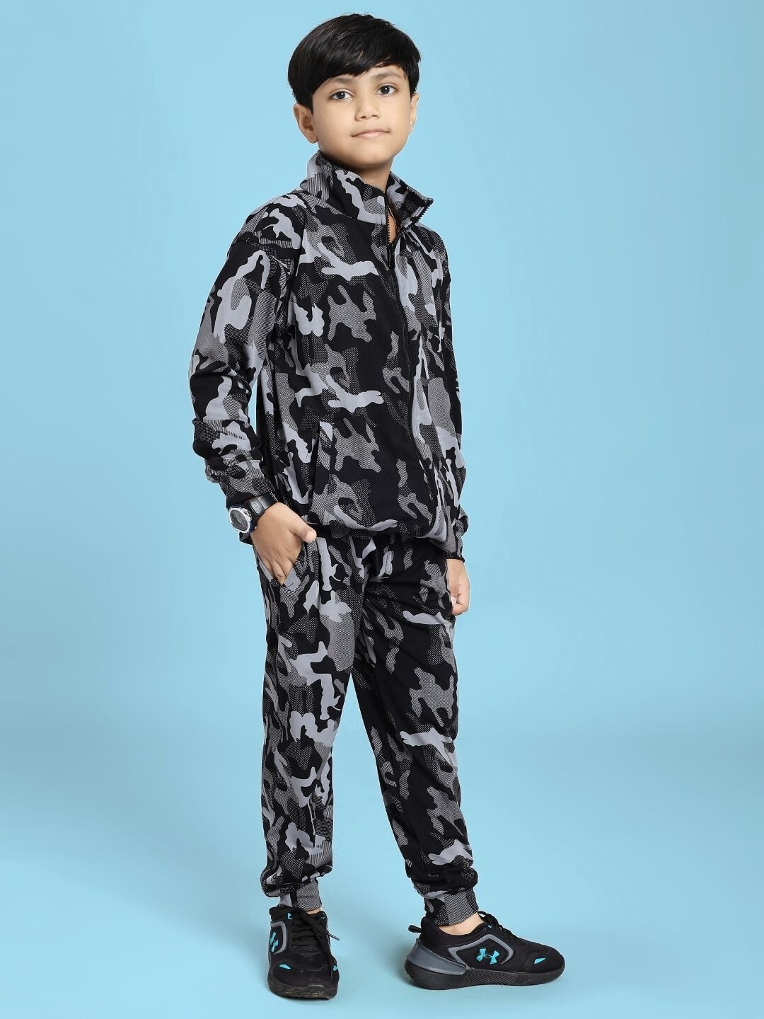 A child wearing a DEFENCE CO-ORD SET FOR BOYS AND GIRLS BLACK GREY standing confidently against a blue background.