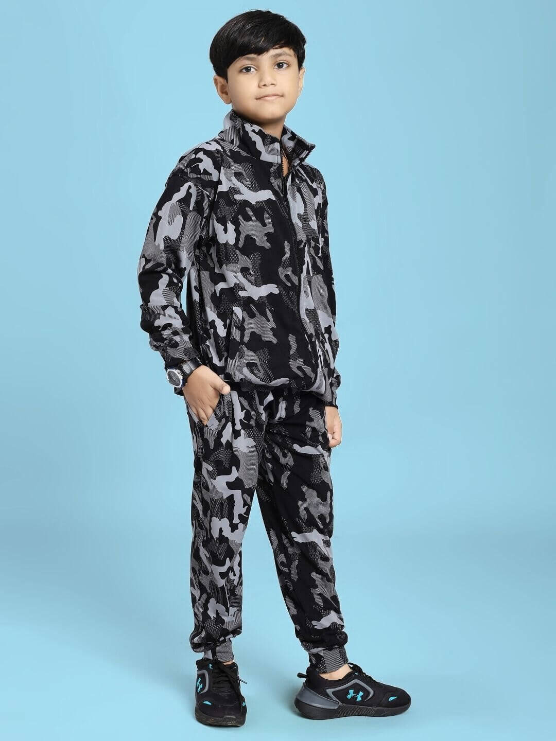 A child wearing a DEFENCE CO-ORD SET FOR BOYS AND GIRLS BLACK GREY standing confidently against a blue background.