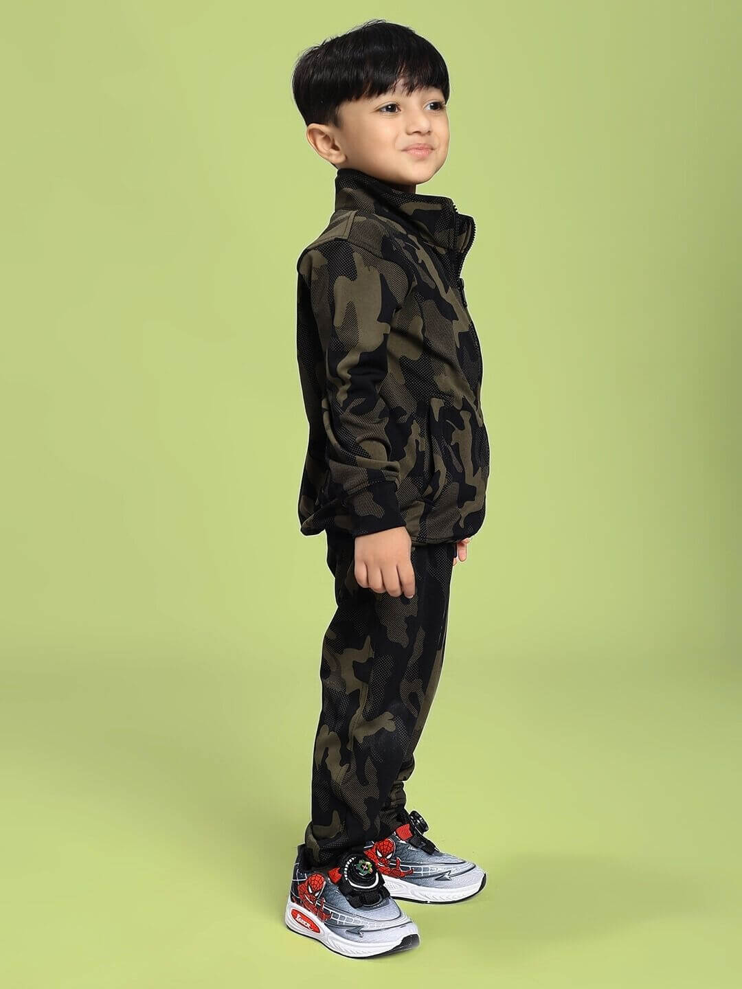 Child wearing DEFENCE CO-ORD SET FOR BOYS AND GIRLS CAMO GREEN, featuring a stylish camouflage pattern, standing against a green background.