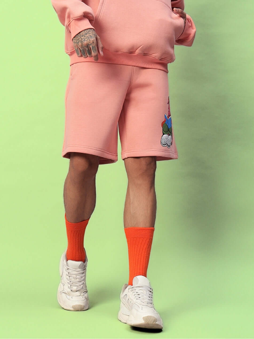 Person wearing DELIBERATE FLEECE SHORTS PEACH with socks and sneakers for a casual look.