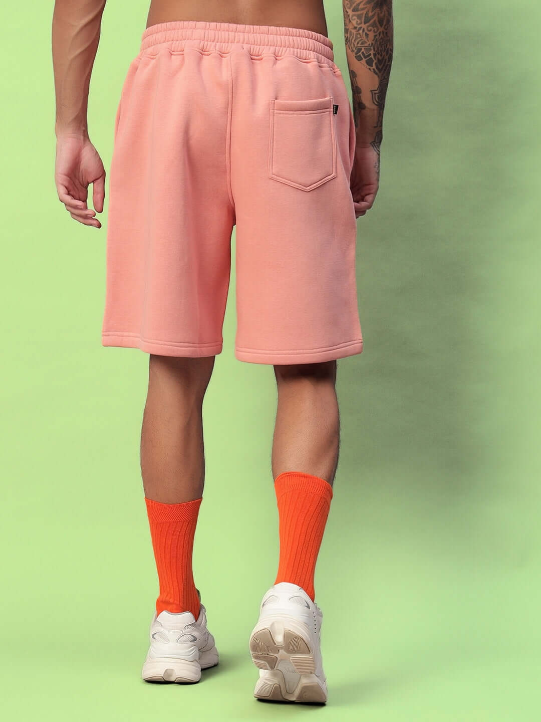 Back view of person wearing DELIBERATE FLEECE SHORTS PEACH, showing soft peach fleece fabric with elastic waistband and rear pocket.