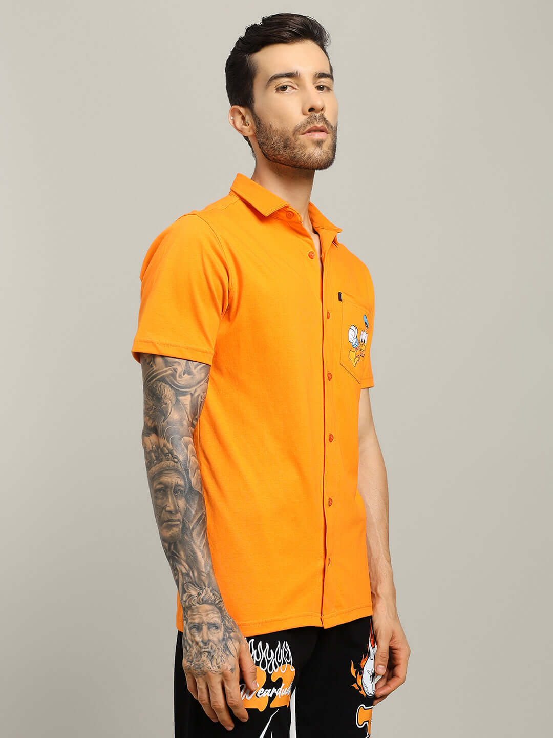 Model wearing DELLA REGULAR FIT SHIRT ORANGE with tattoos, showcasing vibrant orange color and classic design.