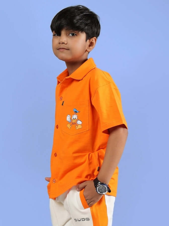 Boy wearing DELLA SHIRT FOR BOYS & GIRLS ORANGE with cartoon graphic, showcasing casual style in vibrant color for kids' fashion.