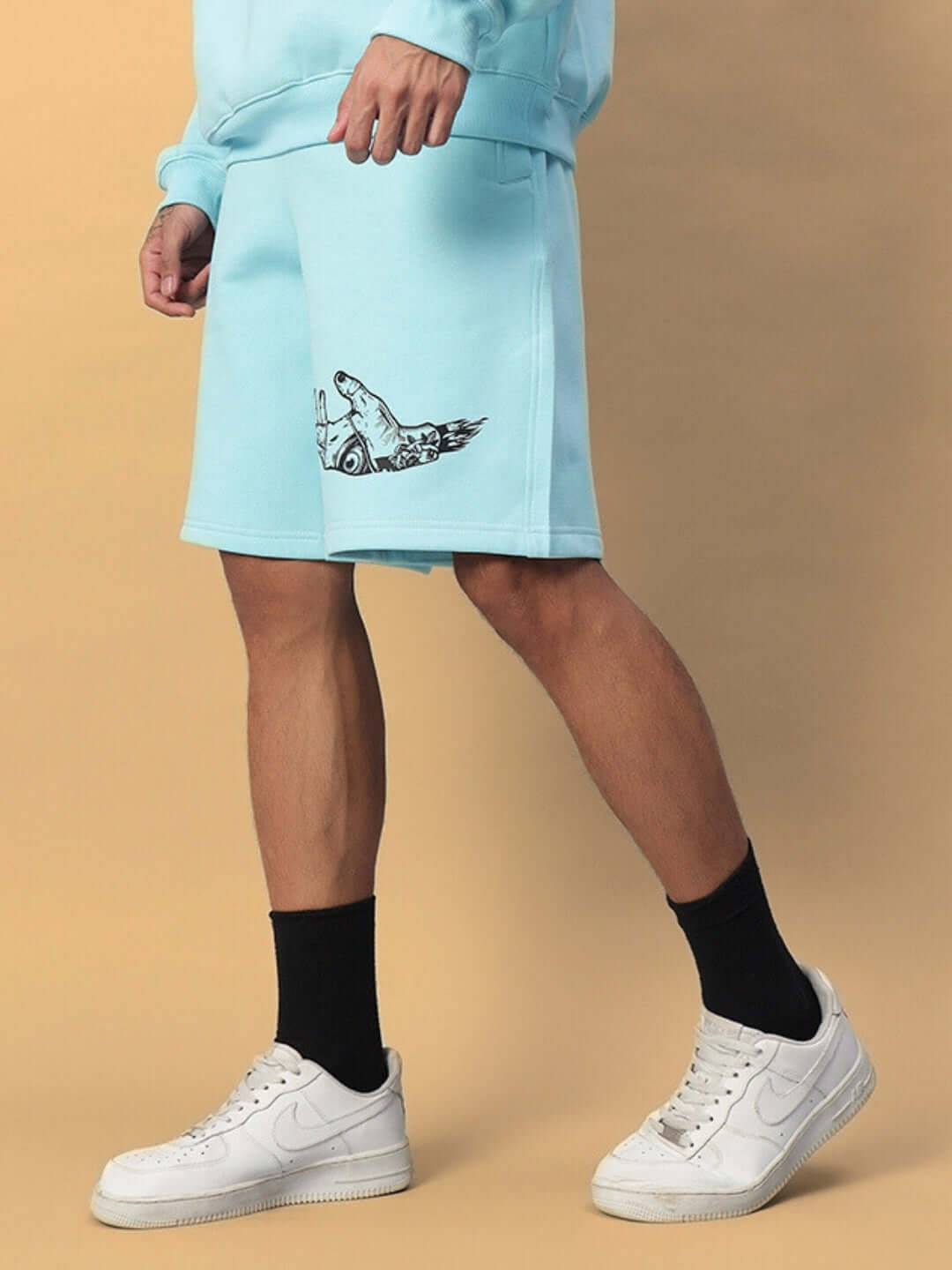 Model wearing WEARDUDS DEMON FLEECE SHORTS SKY BLUE with sneakers, showcasing side view and design detail.