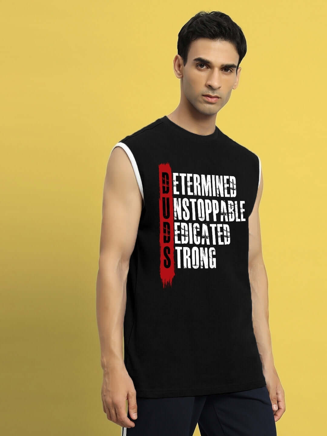 Man wearing a black sleeveless gym t-shirt with 'DETERMINED PRINT GYM T-SHIRT BLACK' text emphasizing strength and dedication.