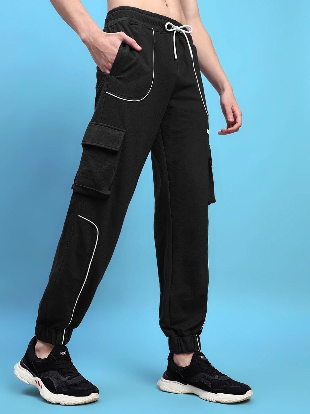 Model wearing DEVENO relaxed-fit black joggers with white piping, adjustable drawstring, and cargo pockets, showcasing sporty casual style.