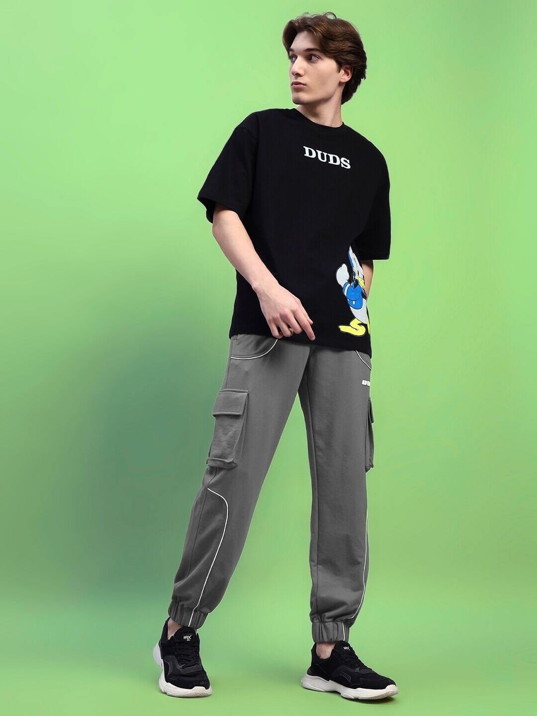 Model wearing Deveno Relaxed-Fit Joggers Grey with a black graphic t-shirt and sneakers, showcasing comfort and modern style.