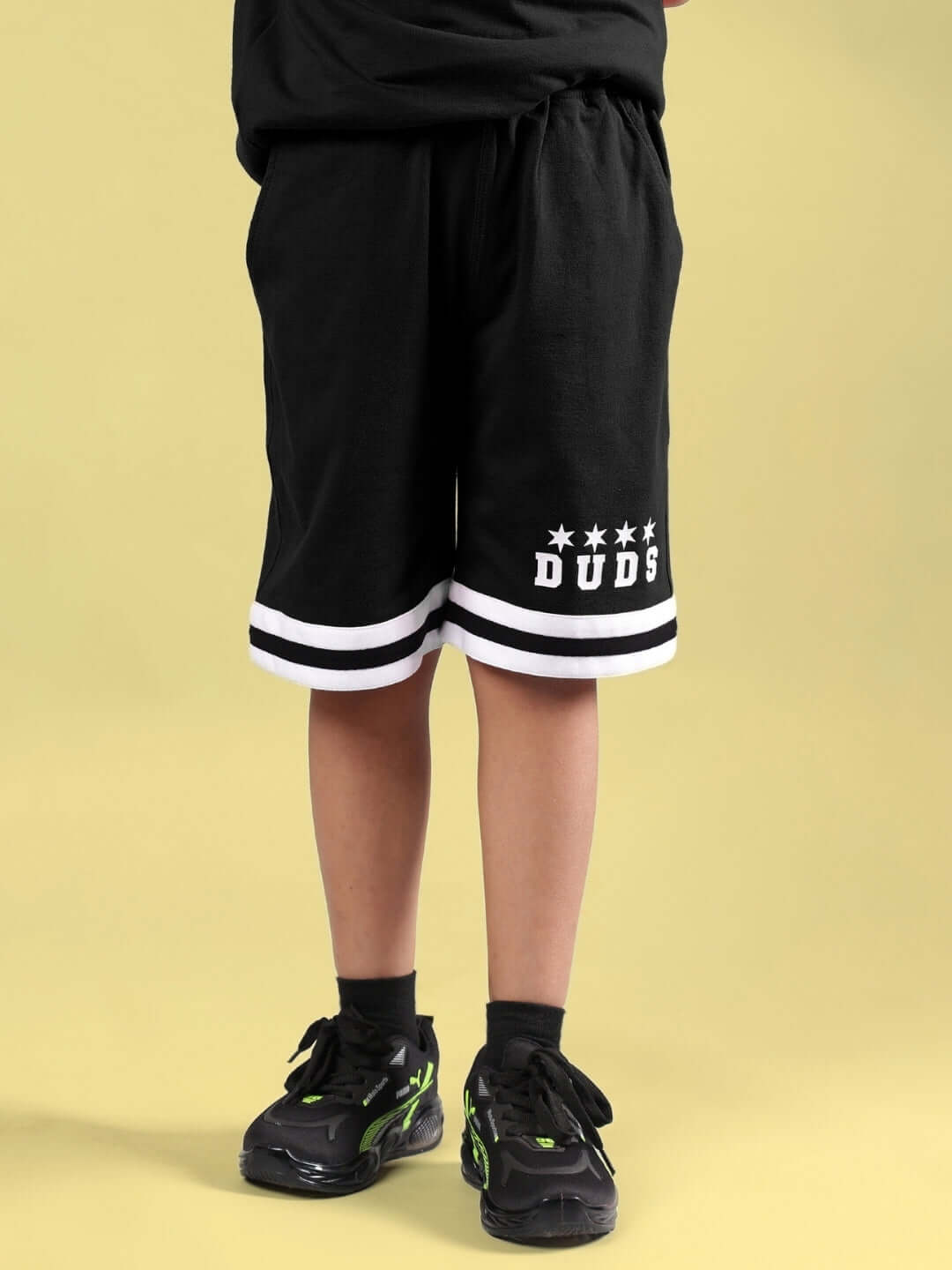 Child wearing DIGGIN SHORTS FOR BOYS & GIRLS BLACK by Duds with white stripes on a yellow background