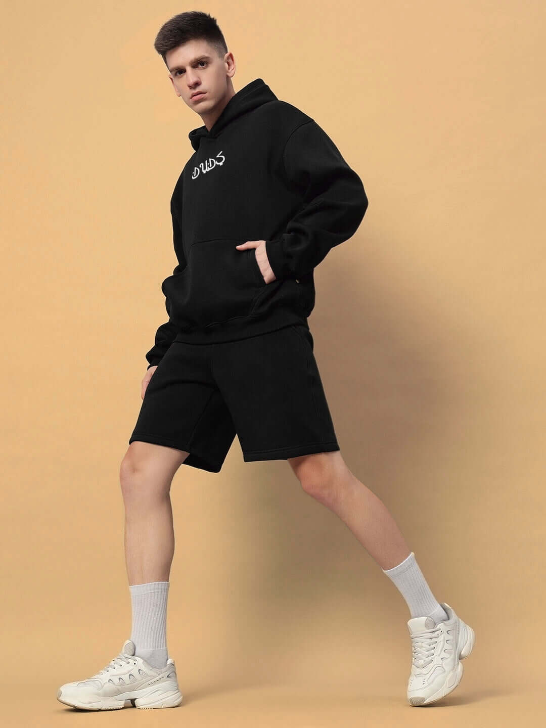 Model wearing DIMENSION COTTON FLEECE CO-ORD BLACK, featuring a hoodie and shorts set, styled with sneakers for a chic, casual look.