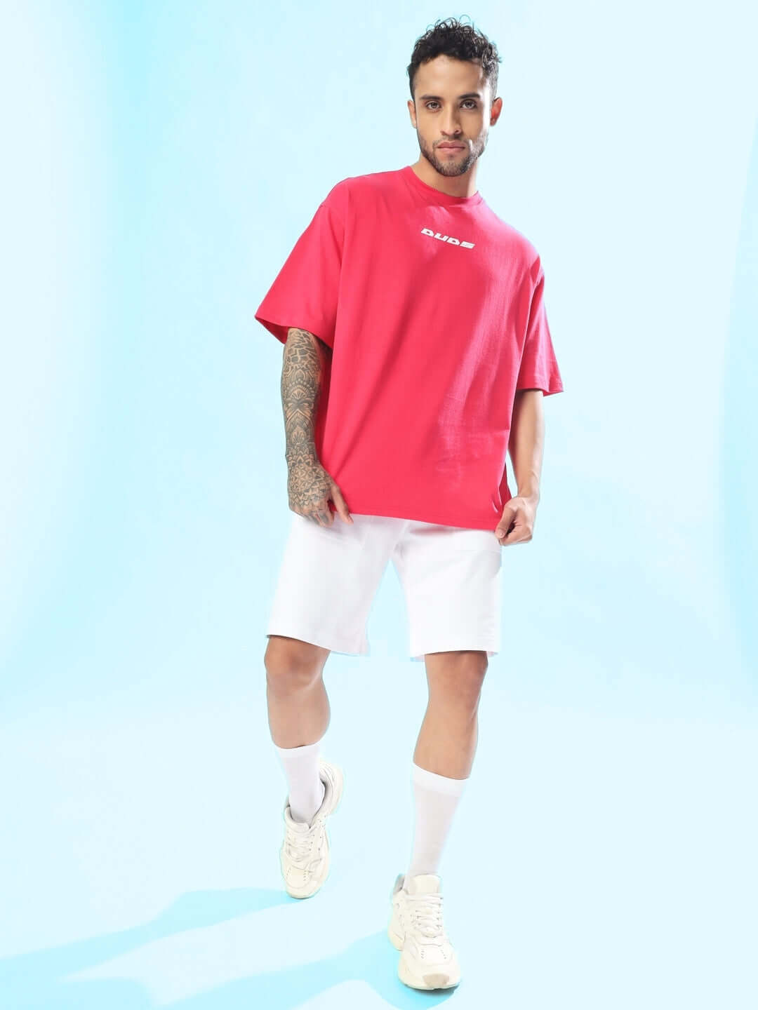 Man wearing Disney Lilo oversized pink t-shirt, paired with white shorts and sneakers. Casual fashion style.