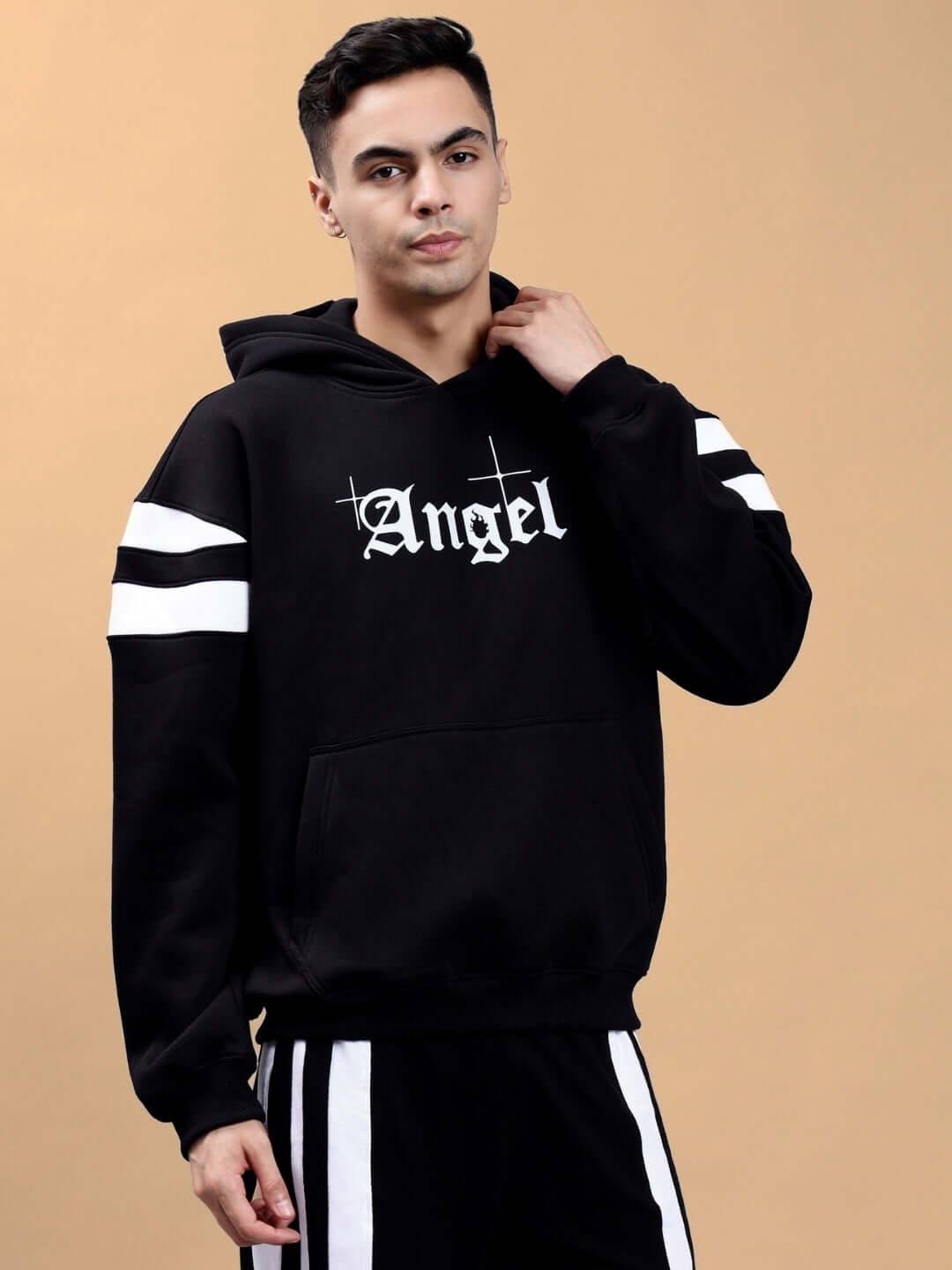 Model wearing a black colorblock oversized hoodie with 'Angel' text, featuring white sleeve stripes, front view against a neutral background.