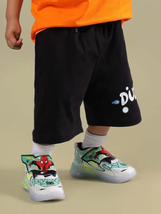 Child wearing DIVING BEAR SHORTS FOR BOYS & GIRLS BLACK with colorful sneakers.