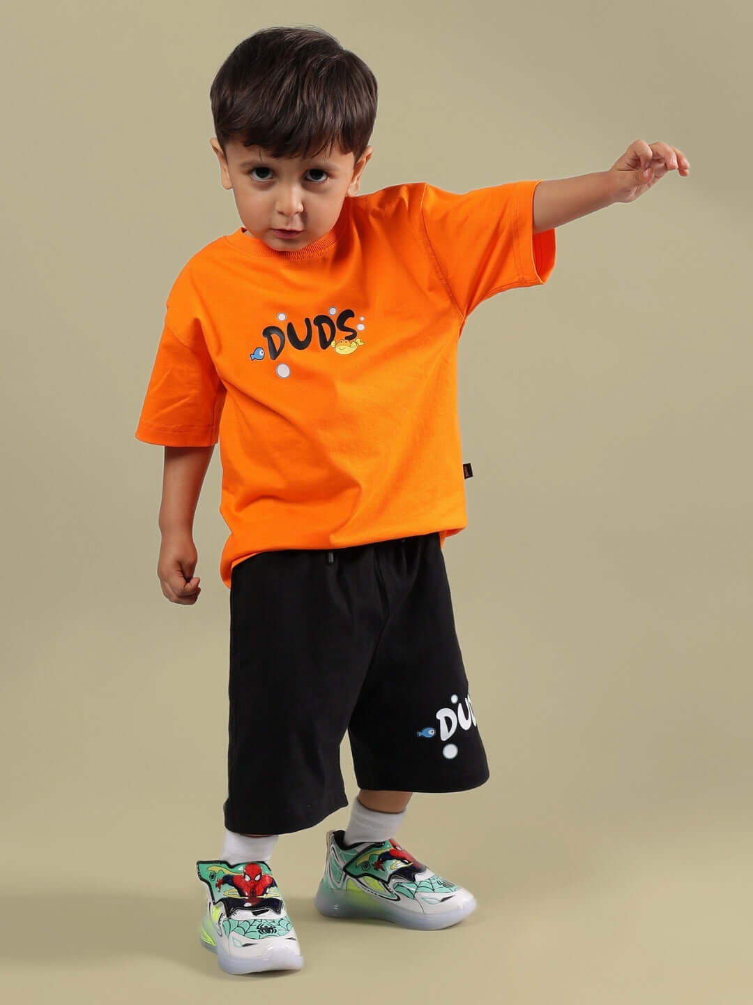 Boy wearing a bright orange DIVING BEAR T-SHIRT FOR BOYS GIRLS ORANGE with a playful stance, paired with black shorts.