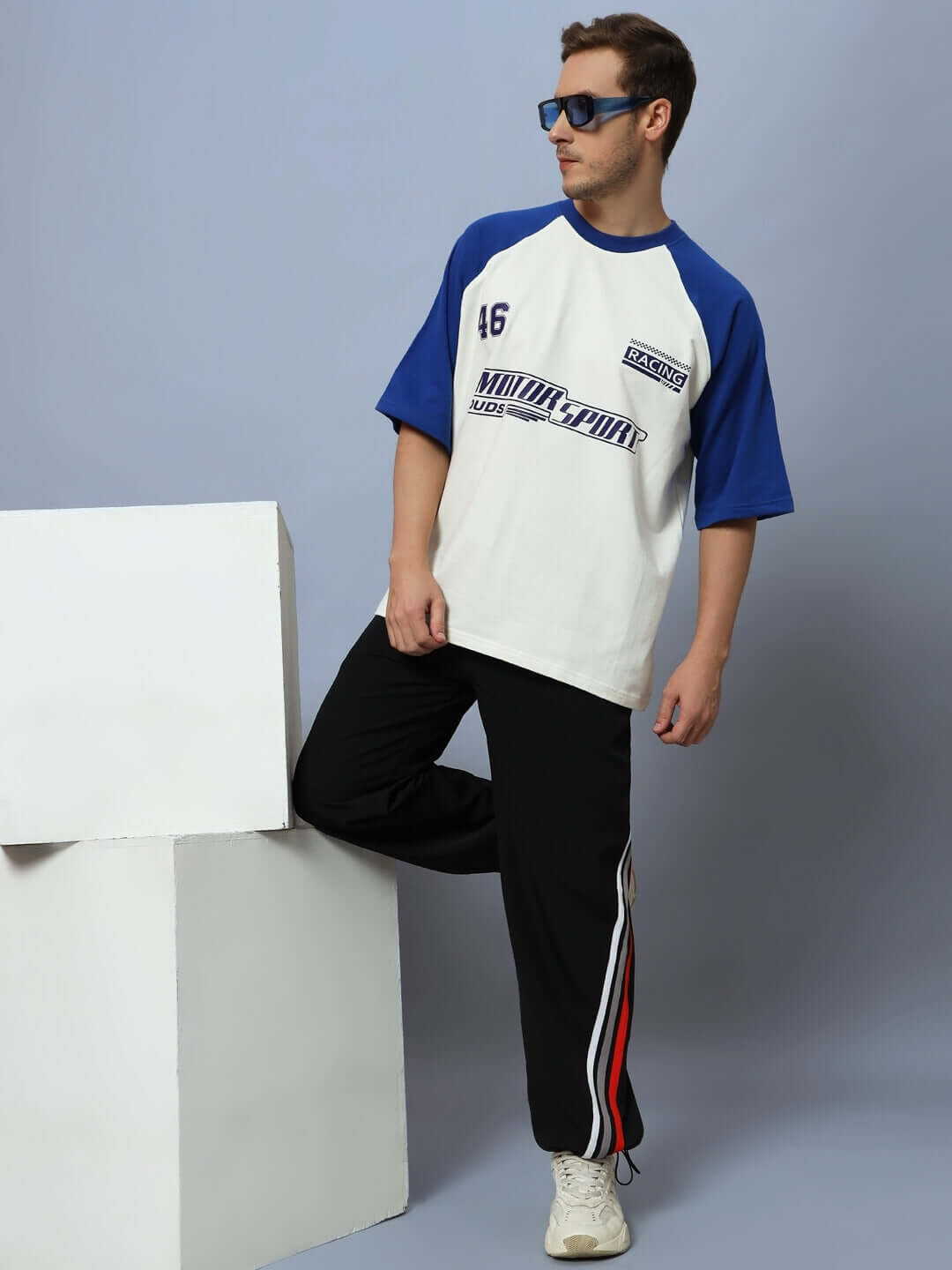 Model wearing black Dobbin relaxed fit joggers with a blue and white shirt, standing in a stylish pose against a minimalistic backdrop.