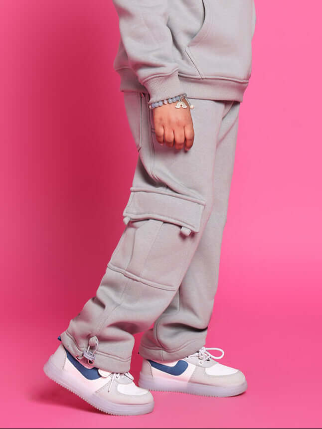 Grey Dream Fleece Pant for Boys and Girls, comfortable and stylish, paired with sneakers against a pink background.