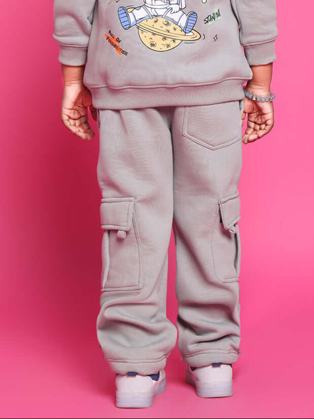 Child wearing grey Dream Fleece Pants for boys and girls, featuring comfortable fit and side pockets against a pink background.