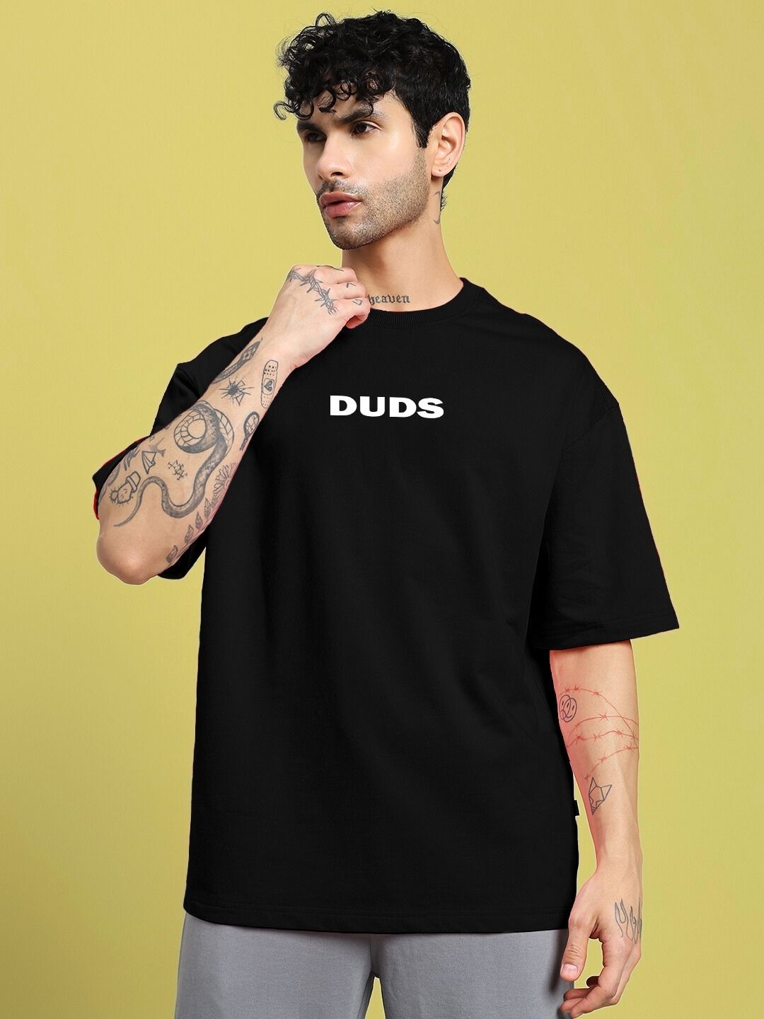 Model wearing DREAMLESS OVER-SIZED T-SHIRT BLACK with bold textual design on front.