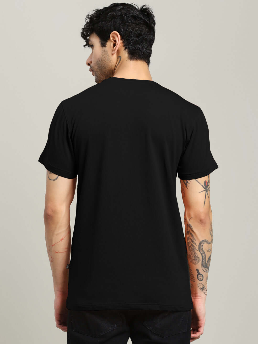 Back view of man wearing DREAMS REGULAR FIT T-SHIRT BLACK, showcasing comfortable fit and classic color.