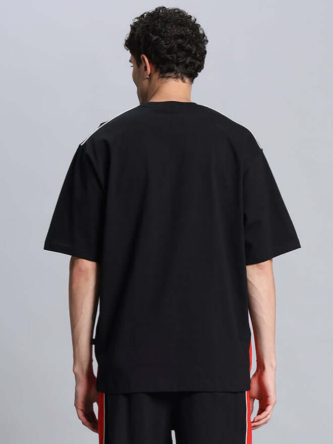 Back view of a model wearing a black DRIFT oversized t-shirt, highlighting the relaxed fit and casual style.