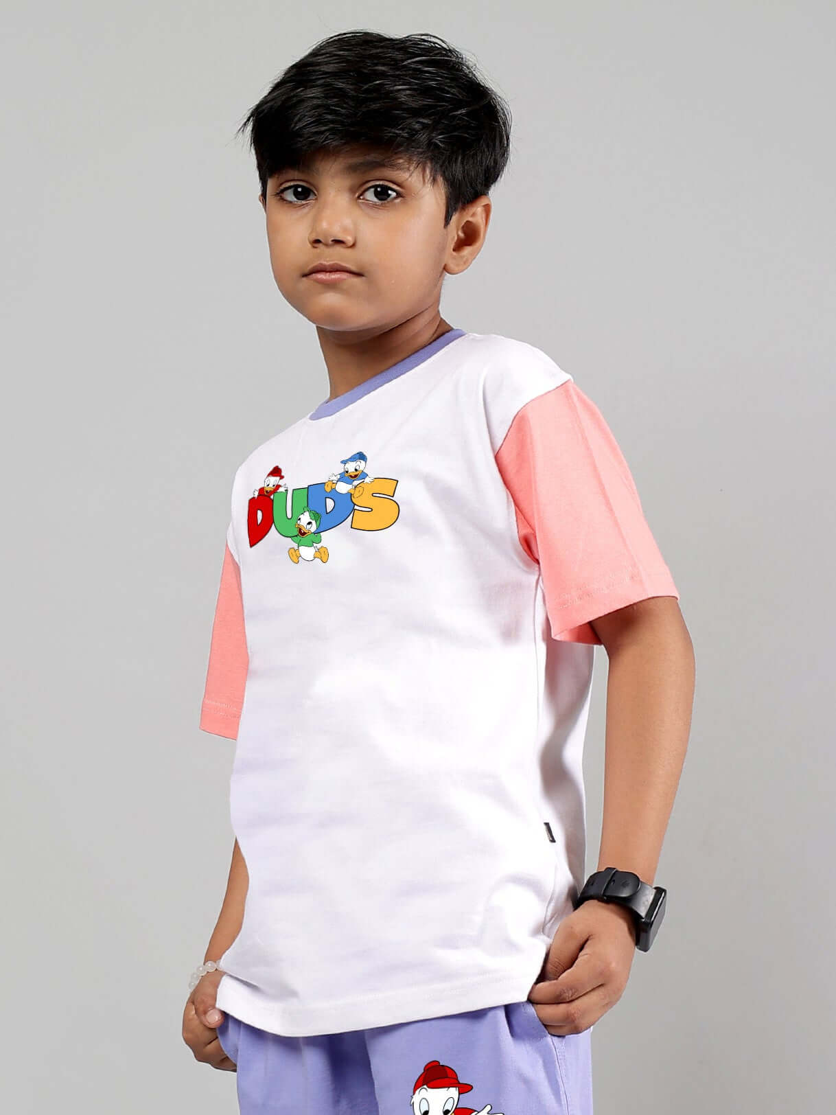 Child wearing a white and pink DUCK PLAY T-Shirt by DUDS, suitable for boys and girls, showcasing vibrant colors and cartoon design.