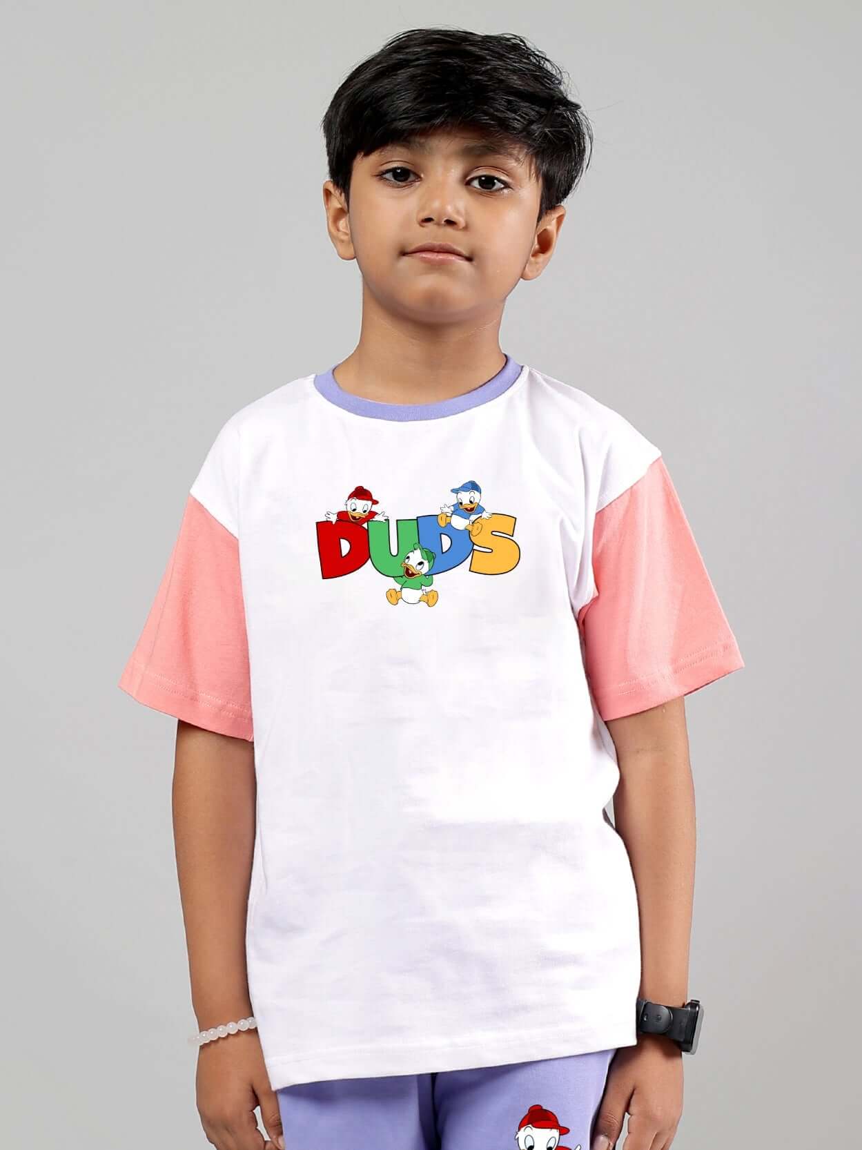 Child wearing DUDS white-pink Duck Play T-shirt, suitable for boys and girls, featuring colorful cartoon ducks on the front.