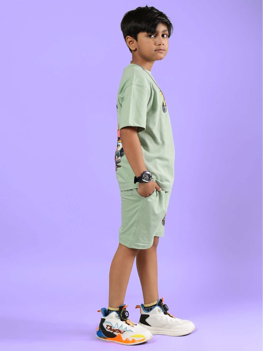 Child wearing DUCK TALES CO-ORD FOR BOYS & GIRLS NYANZA GREEN outfit, side view against a purple background.
