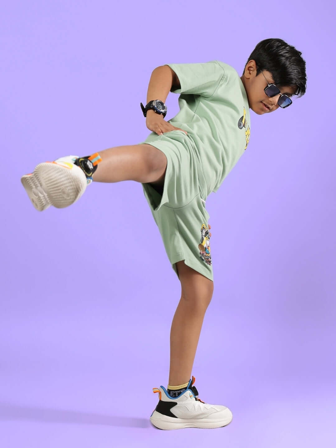 Child wearing DUCK TALES T-SHIRT FOR BOYS GIRLS NYANZA GREEN in active pose on purple background.